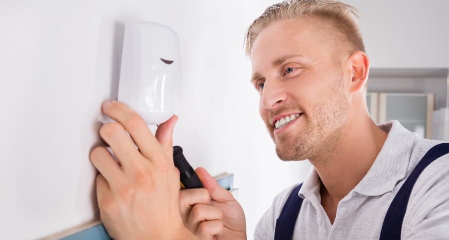 Man placing a motion sensor inside a home